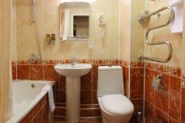 Маленькая ванная комната с белой сантехникой и полотенцами